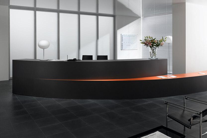 Hotelrezeption mit schwarz lackierter Empfangstheke und orangenem Kontrast