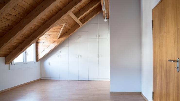 Nischenlösung für weißen Einbauschrank mit Schubladen und Türen an in dunklem Holz belassener Dachschräge