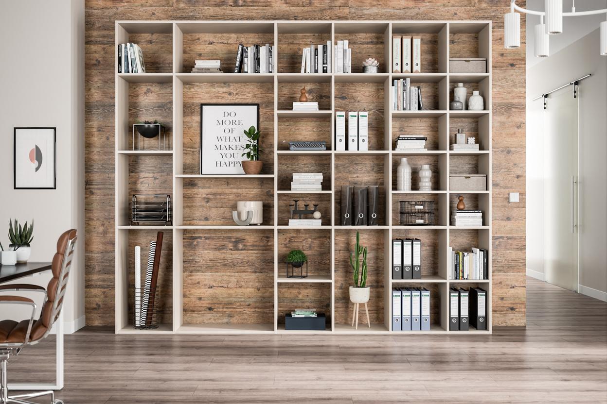 Ein großes, helles Regal nach Maß, gefüllt mit Büchern und Dekorationen, vor einer Wand mit Holzoptik.