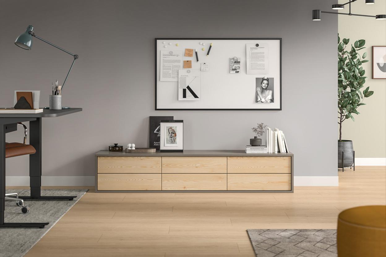 Wohnraum mit hellem, maßgeschneidertem Sideboard aus Holz, darüber eine Pinnwand und Dekorationen.