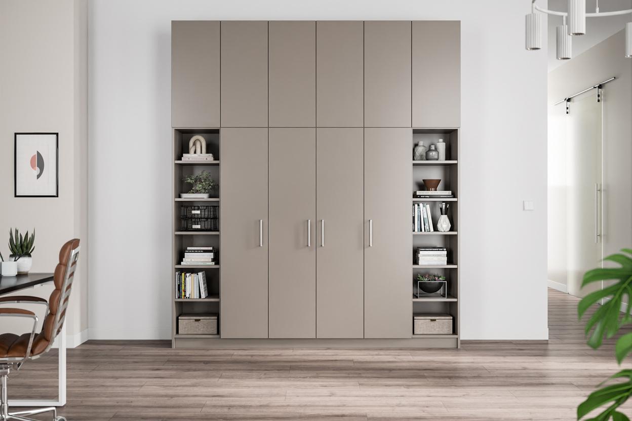 Ein maßgefertigter, taupefarbener Schrank mit glatten Türen, flankiert von offenen Bücherregalen mit diversen Dekorationsobjekten und Aufbewahrungsboxen.