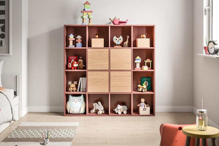Ein Schrank nach Maß in Terrakottafarbe mit offenen und geschlossenen Fächern, befüllt mit Spielzeug und Büchern, bietet spielerische Ordnung im Kinderzimmer.