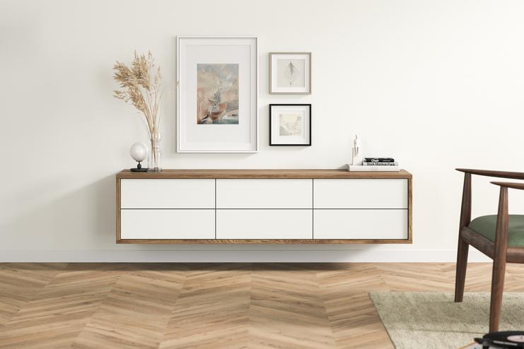 Ein minimalistisches, maßgefertigtes Hängeboard aus Holz mit weißen Schubladen, unter eingerahmten Bildern, verleiht diesem Wohnbereich ein stilvolles Flair.
