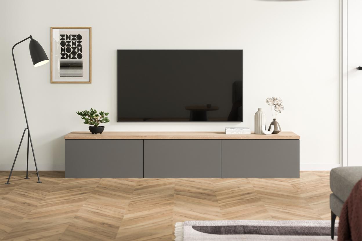 Maßgefertigte, dunkelgraue Kommode unter einem Flachbildfernseher, kombiniert mit einer warmen Holzplatte, minimalistischer Dekoration und einem schwarzen Stehlampe daneben.