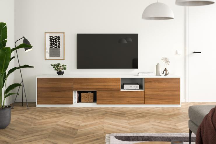 Eine minimalistische Kommode nach Maß, mit Holzelementen und weißen Fronten, steht unter einem Wand-TV, umgeben von stilvoller Dekoration.